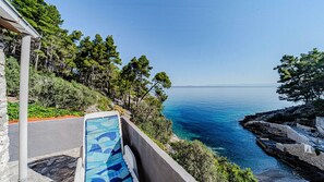 A balcony with a view of the sea, surrounded by trees and rocky terrain. - Robinson’s House Maya by Villas Guide (Blato)