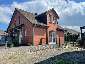 Ein zweigeschossiges Haus mit Backsteinfassade, Ziegeldach und befestigter Auffahrt.