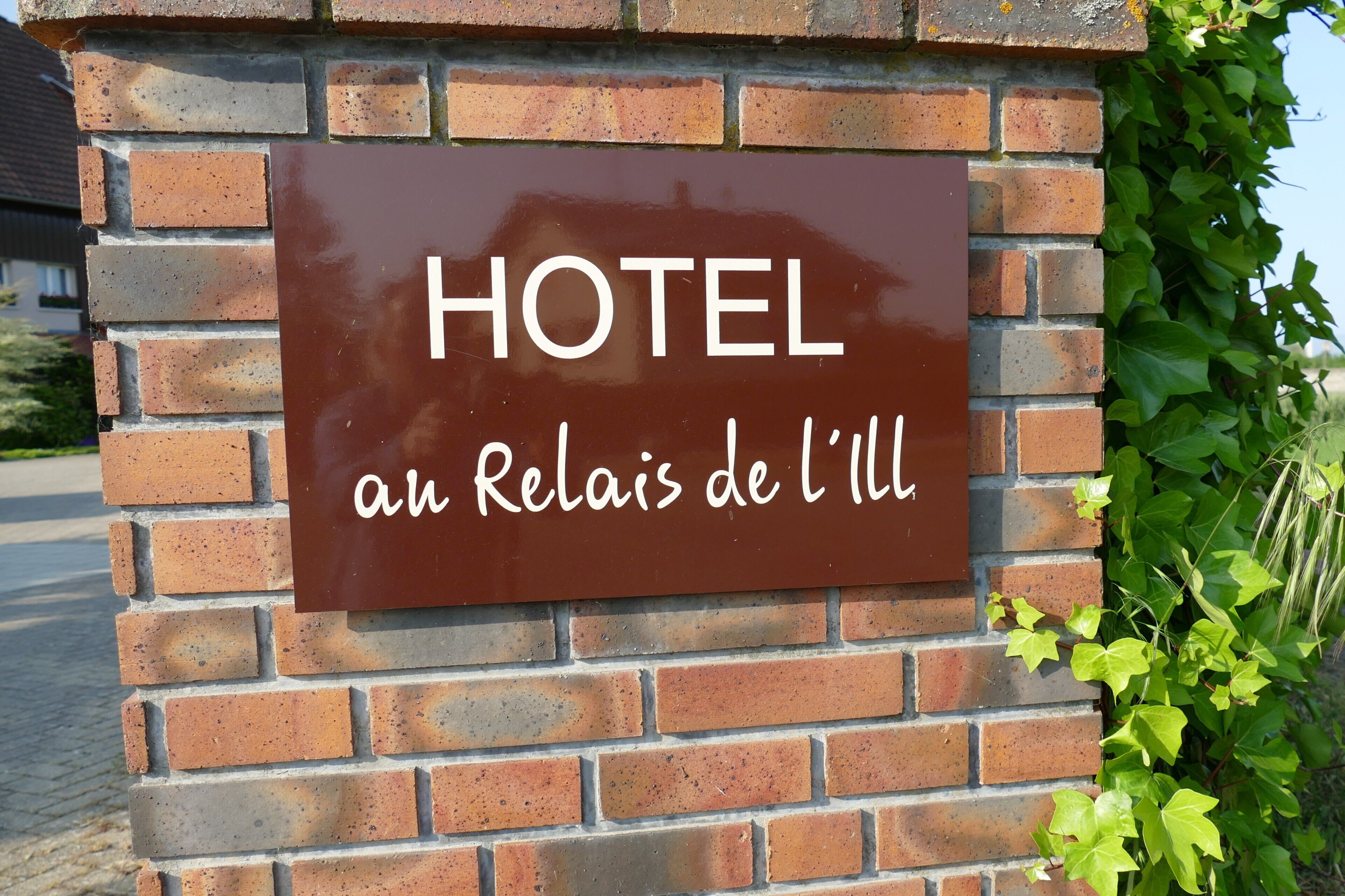 A sign with 'HOTEL' and 'an Relais de l'Ill' text on a brick wall.