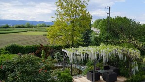 Une terrasse de jardin agrémentée d’une pergola, d’un espace salon et offrant une vue sur un champ et des montagnes.