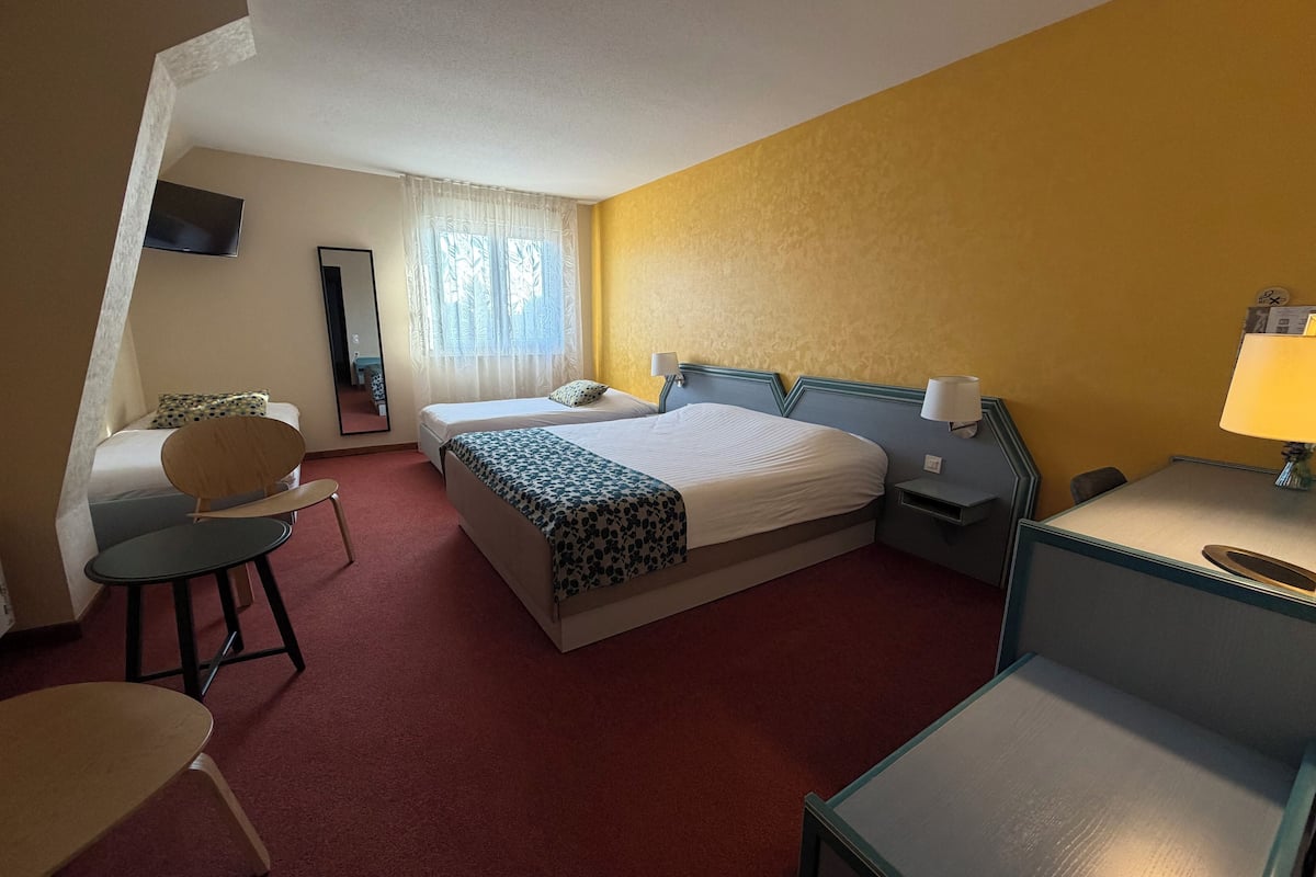 A hotel room with a bed, two bedside tables, a desk, a chair, and a TV.