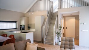 A modern interior with a staircase, a dining area, a kitchen, and a living room.