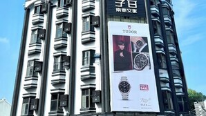 Un immeuble à plusieurs étages sur lequel est affichée une grande publicité pour les montres Tudor.