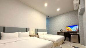 Une chambre d’hôtel avec deux lits, un bureau avec une télévision et un petit réfrigérateur.