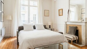 Quarto de hotel com uma cama grande, lareira, mesa de vidro e vista para a cidade.