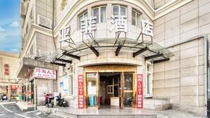 Ein Hotel mit gebogenem Fassadenteil, großen Glasfenstern und Hinweisschildern, die es als Hotel kennzeichnen.