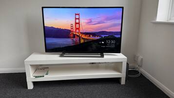 A flat-screen TV on a white TV stand in a room with carpeted flooring.
