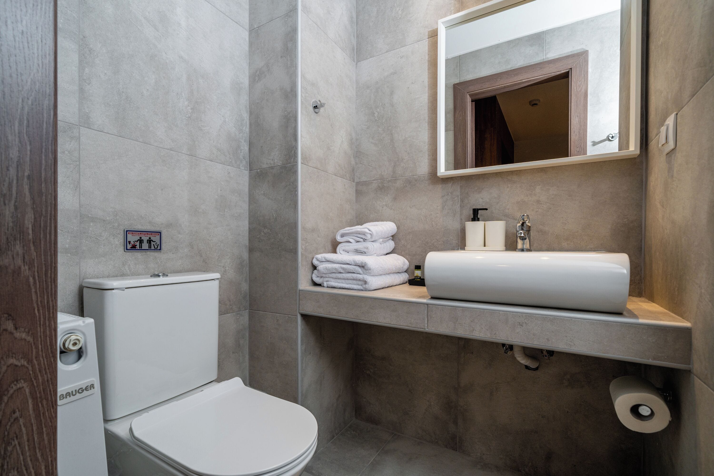 A modern bathroom with a toilet, a sink, and a mirror.