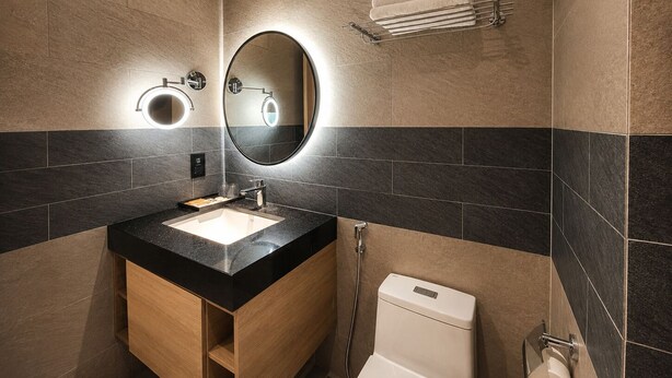 A modern bathroom with a sink, mirror, towel rack, and toilet. - Cita Residence Ha Long (Bai Chay)