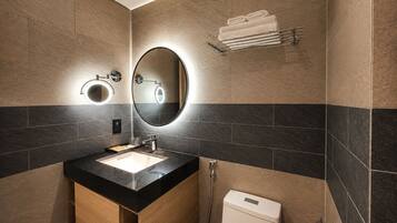 A modern bathroom with a sink, mirror, towel rack, and toilet.