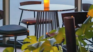 Une table avec une bougie, des chaises et une vue sur un plan d’eau et des montagnes.