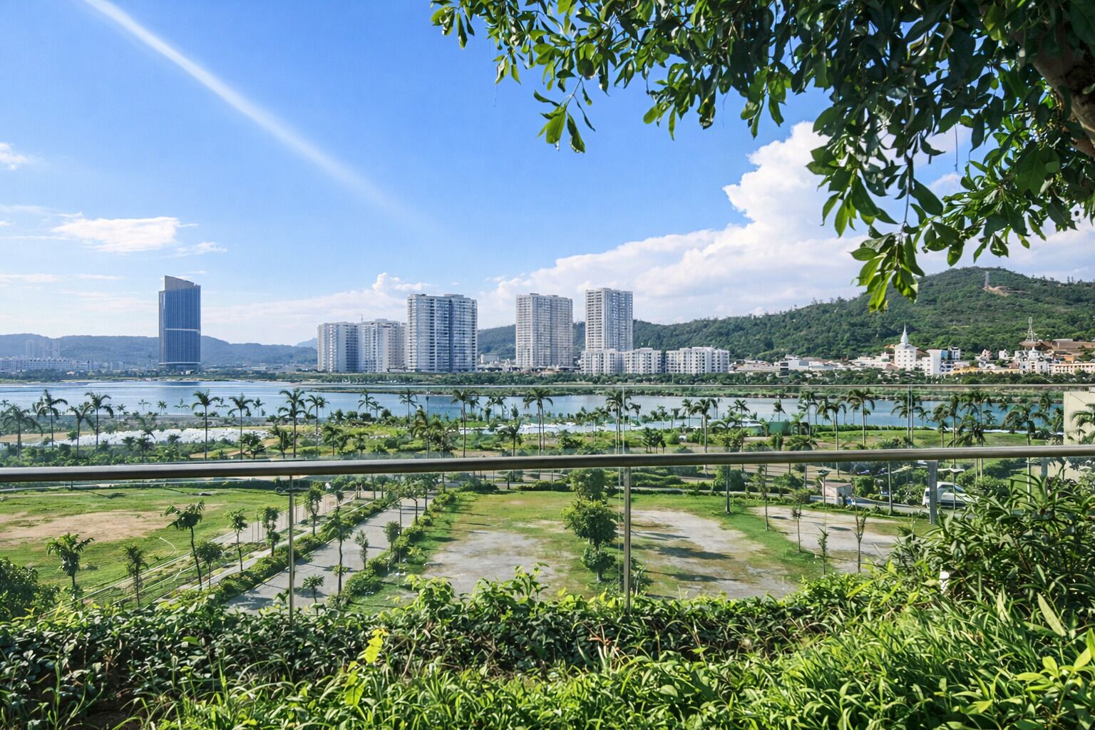 A coastal cityscape with high-rise buildings, a marina, and a lush green park area.