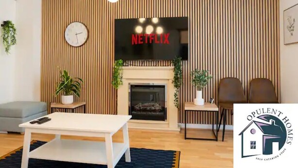 Un soggiorno moderno con camino, una televisione montata sopra e un'area pranzo con sedie e tavolo.