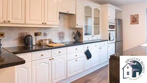 Una cucina moderna con mobili bianchi, un piano di lavoro nero e un frigorifero in acciaio inossidabile.
