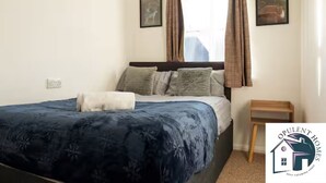 Una camera da letto con un letto, un comodino e una finestra con tende.