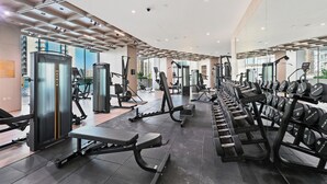 A modern gym with various exercise equipment, including treadmills, weight machines, and dumbbells. - Bloomfields Iconic 1BR Binghatti Phanto (Dubai)