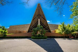 A building with a triangular roof structure, surrounded by a paved area and palm trees. - Casa del Mar Tropical Sanctuary (Jacó)