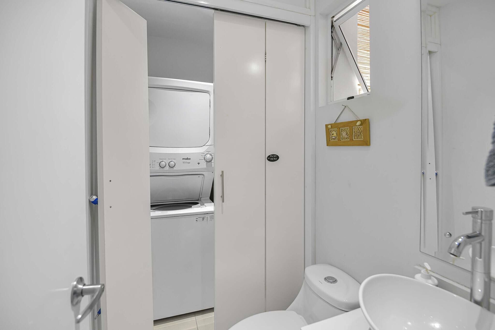 A compact, modern bathroom with a built-in washer and dryer, a toilet, and a sink.
