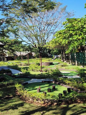 A well-maintained garden with various plants and trees, a pathway, and a small pond. - Casa del Mar Tropical Sanctuary (Jacó)