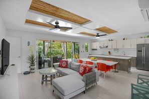 A modern kitchen with a central island, white cabinets, and a built-in refrigerator. - Casa del Mar Tropical Sanctuary (Jacó)