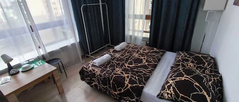 A hotel room with a bed, a desk, and a window.