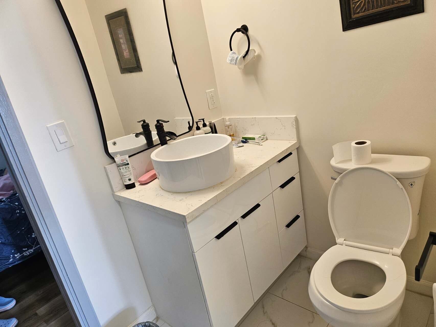 Un bagno con lavandino, WC e specchio bianchi.