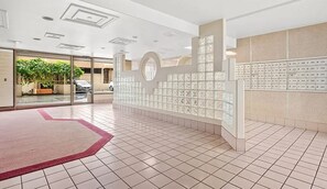 Eine Hotelhalle mit einer Rezeption, einem Glastür-Eingang und einem gefliesten Boden.