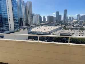A high-rise building with a modern glass facade, a parking lot with several cars, and a clear blue sky. - 2-bedroom1.5bath apartmentNearWaikikiBeach  /Close to Hospital&Schools (Honolulu)