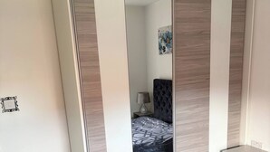 Ein Schlafzimmer mit Bett, Nachttisch, Schreibtisch und Kleiderschrank.