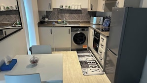 Eine kleine Küche mit Waschmaschine, Mikrowelle und Kühlschrank.