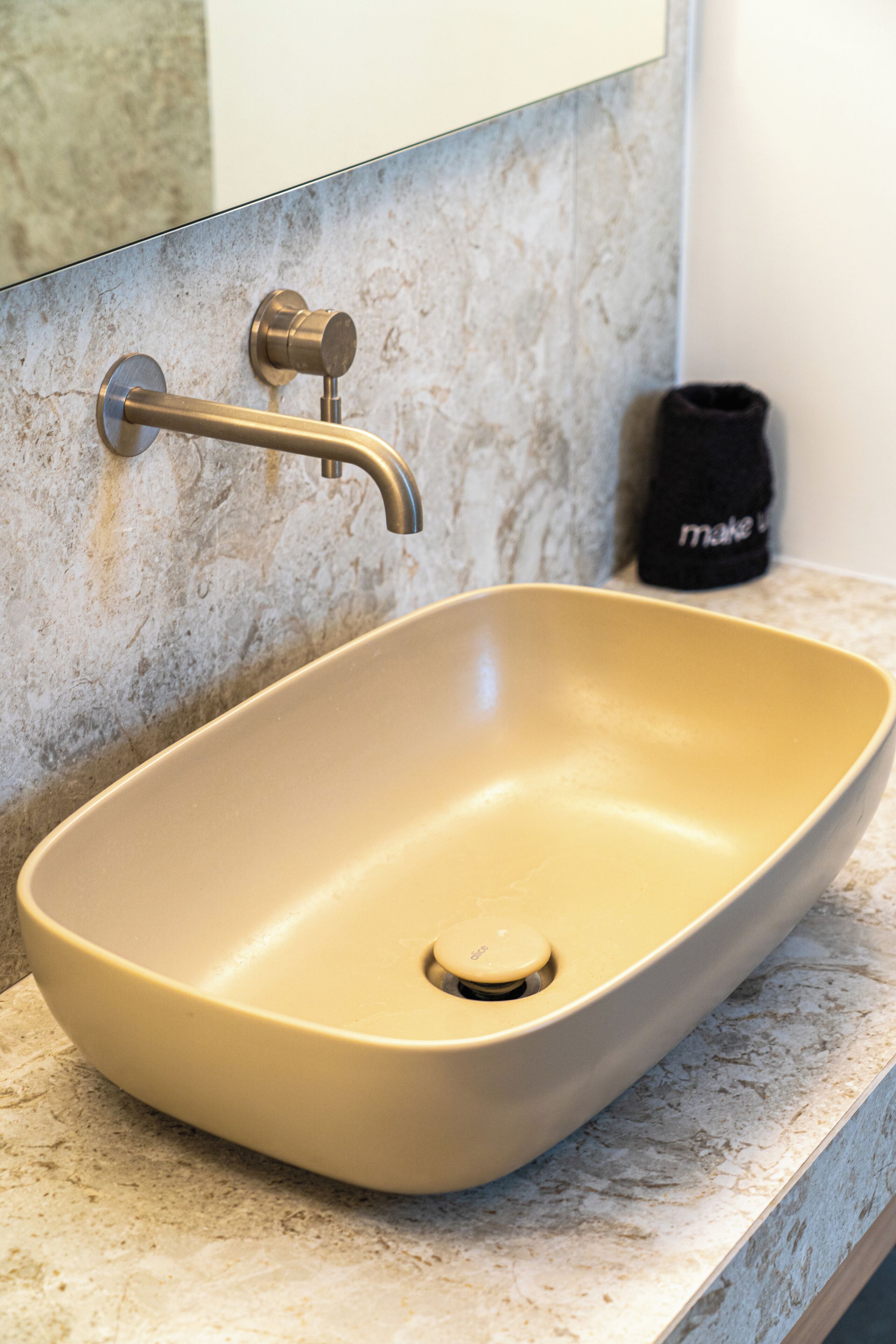 A bathroom with a beige sink, a faucet, and a towel rack.