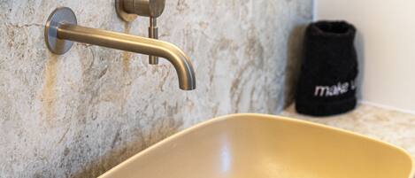 A bathroom with a beige sink, a faucet, and a towel rack.