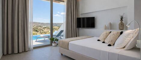 A bedroom with a bed, a TV, a view of the outdoors, and a ceiling fan.