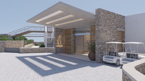 A modern building with a stone facade, a covered entrance, and a golf cart. - Ramnus Karpathos Suites (Karpathos)