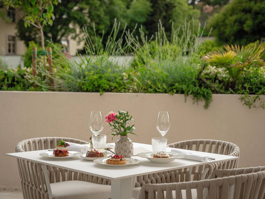 A dining table with plates of food, glasses, and a vase with flowers.