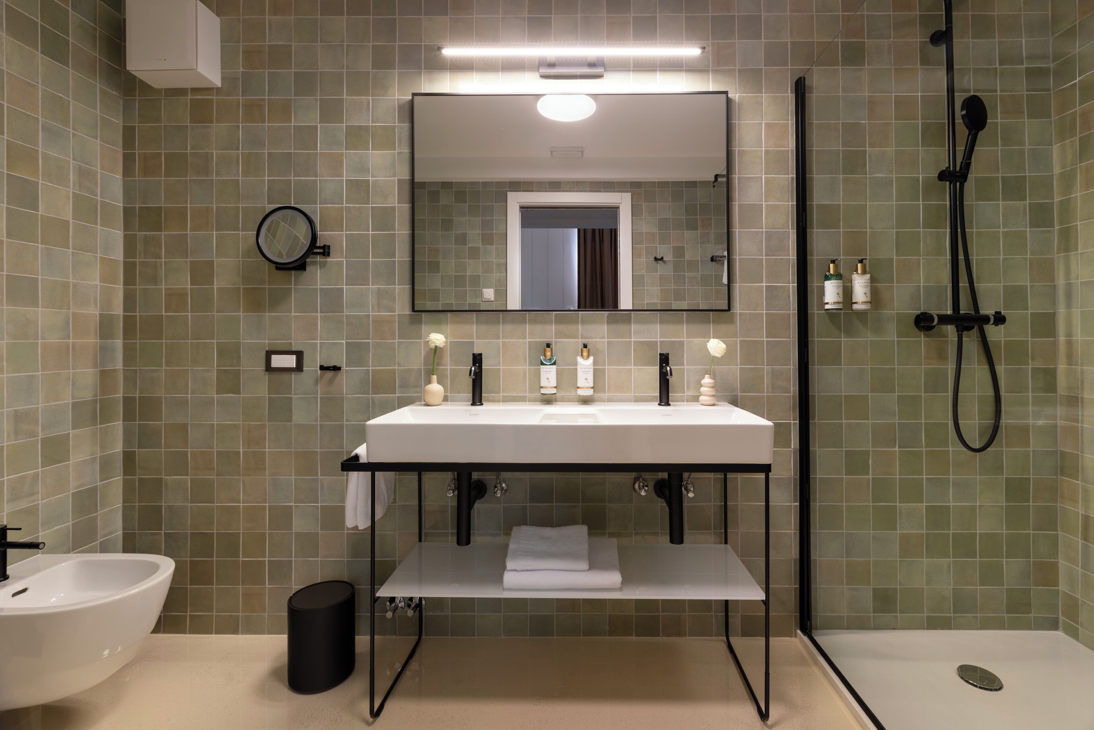 A modern bathroom with a white sink, mirror, and shower.