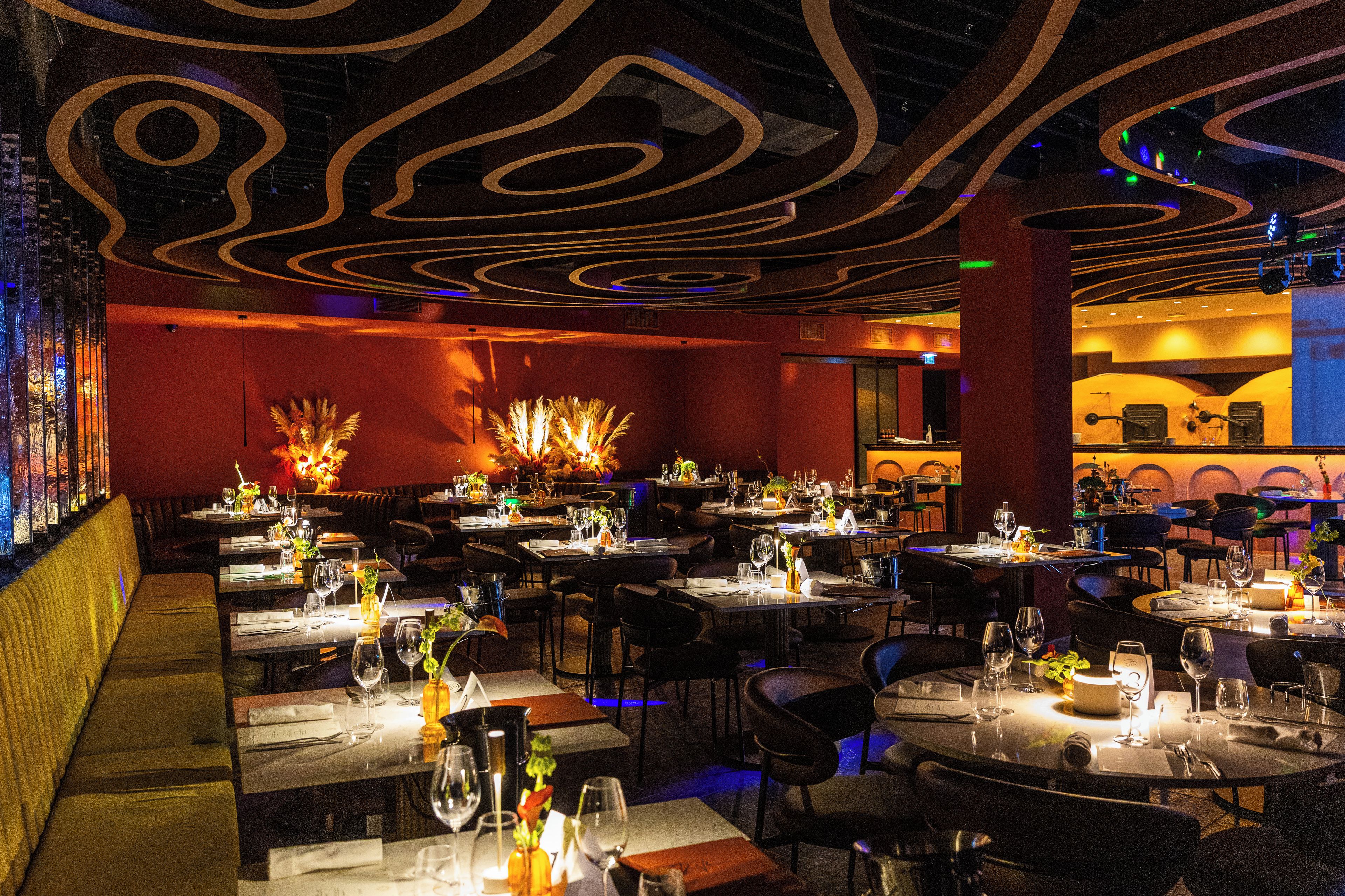 A restaurant interior with multiple dining tables, chairs, and a bar area.