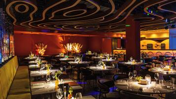 A restaurant interior with multiple dining tables, chairs, and a bar area.