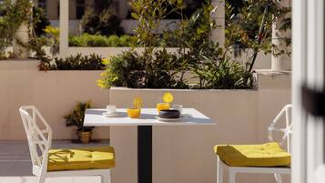 A table with chairs, a potted plant, and a glass of orange juice.