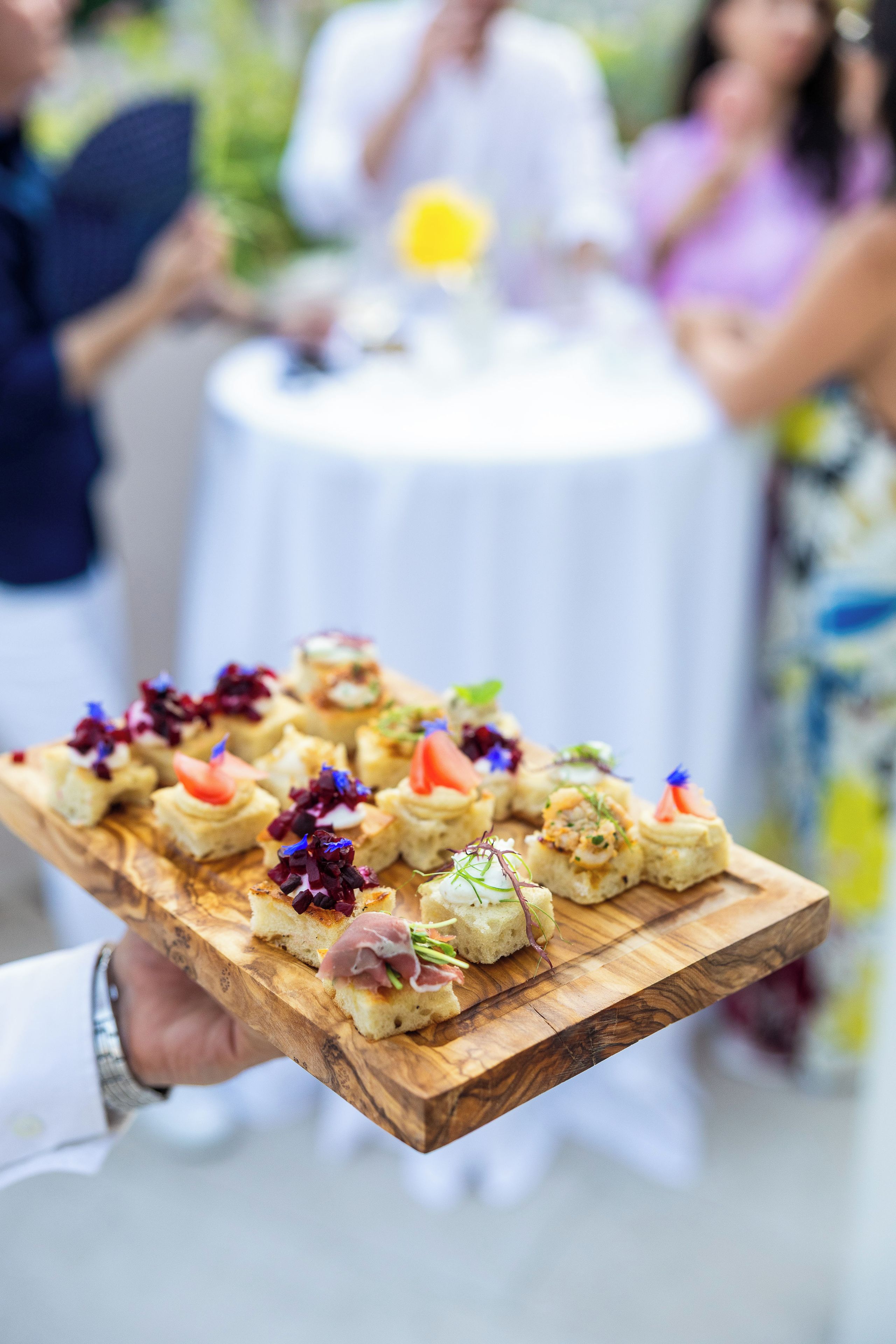 A wooden board with various food items, likely for a catering event.