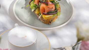 Una mesa con un plato de comida, una taza de café y un jarrón con flores.