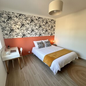 A bedroom with a bed, a desk, a chair, a lamp, and a patterned wall. - 🏆 [SUMMER IN CANNES 2026] Brand-new 3-bedroom apartment—sleeps 6—IN THE CITY CENTER   (Cannes)