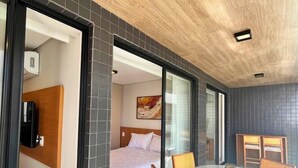 A modern hotel room with a bed, a dining table, and chairs. - LM HYDE PARK (João Pessoa)