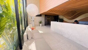 A modern lobby with a reception desk, seating area, and large windows. - LM HYDE PARK (João Pessoa)