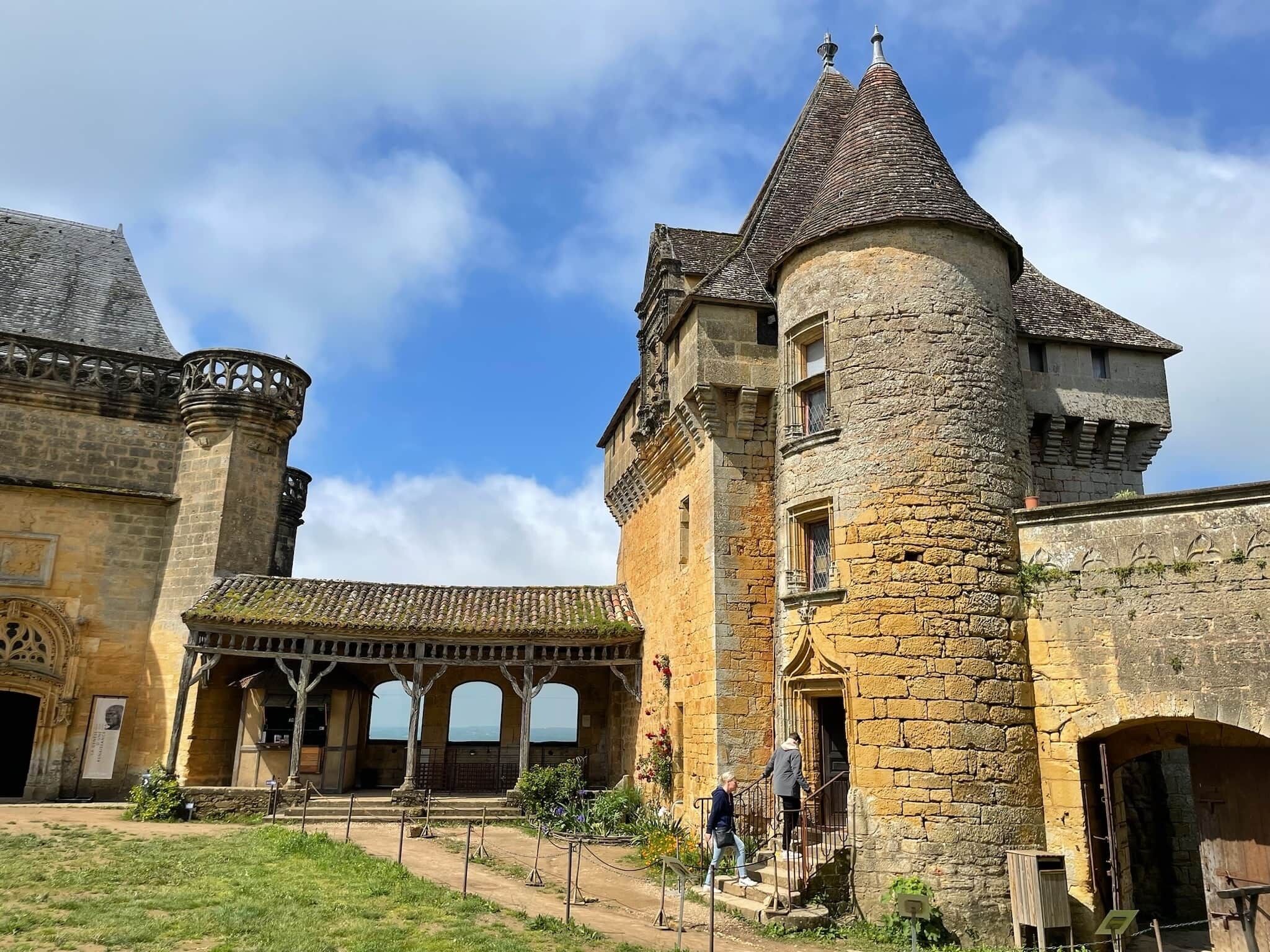 Ein historisches Steinhaus mit Innenhof, überdachtem Gang und einem Turm.
