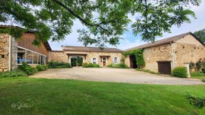 Un bâtiment en pierre avec une allée en gravier et une pelouse verdoyante.