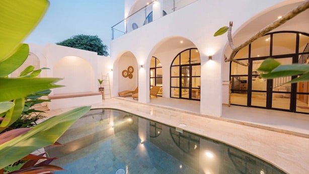 A modern building with a swimming pool, arched windows, and outdoor seating areas. - 2BR Bali Villa Near Uluwatu Surf & Beach Clubs (South Kuta)