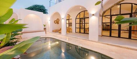 Un edificio moderno con piscina, ventanas arqueadas y zonas de estar al aire libre.