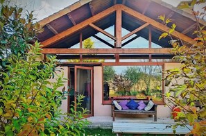 A covered outdoor area with a wooden bench and a sliding glass door leading to a room. - Lamadretierra Country House: Peace and Relaxation, Between the Camino de Santiago and the Medulas   (Villamejil)