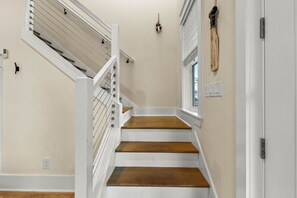 A staircase with white railings and wooden steps, leading to a door with a window.